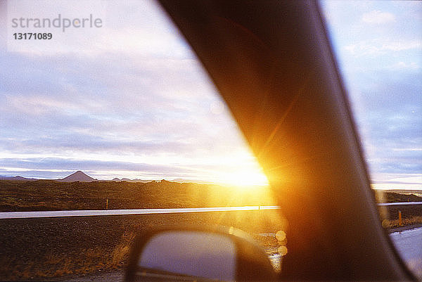 Gerade Landstraße durch ein Autofenster bei Sonnenuntergang  Vesturland  Island