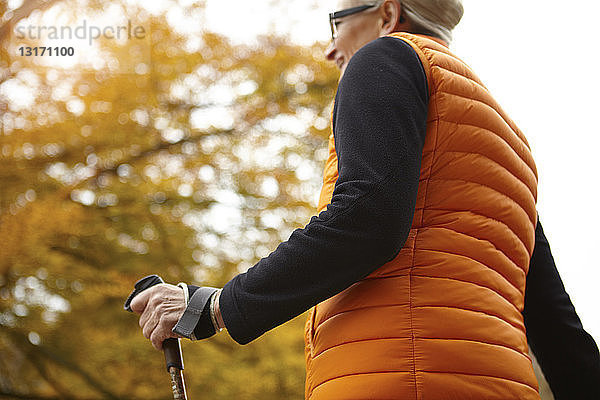 Niedrigwinkelansicht einer älteren Nordic-Walkerin im Herbstpark