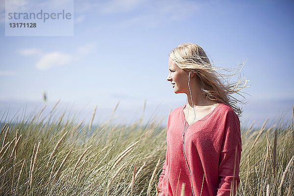 Porträt einer blonden Frau mit rosa Pullover in Strandhafergras  Wales  UK