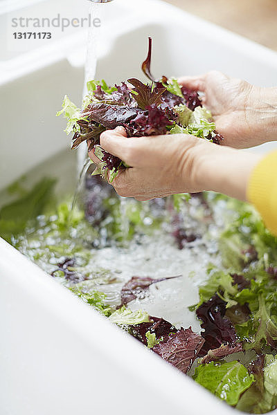 Frau wäscht Gemüse in der Küchenspüle