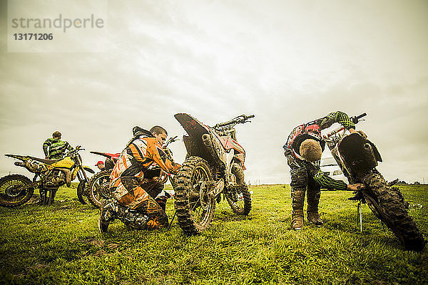 Drei Jungen kontrollieren Motorräder beim Motocross