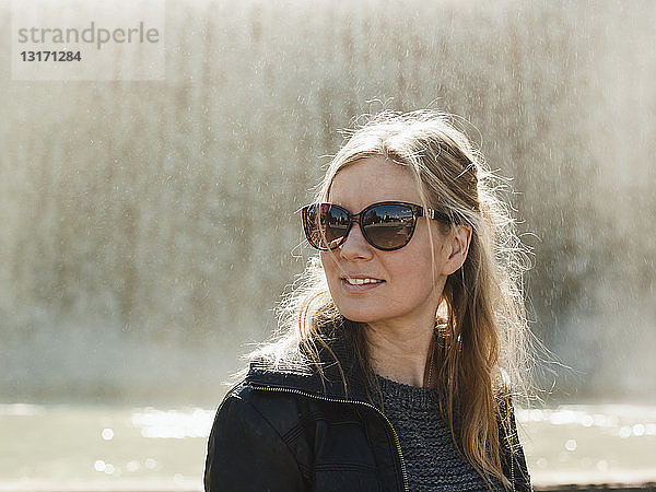 Porträt einer mittleren erwachsenen Frau mit Sonnenbrille vor dem Brunnen auf dem Montjuic-Hügel  Barcelona  Spanien