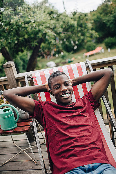 Lächelnder Junge entspannt auf Liegestuhl auf der Veranda