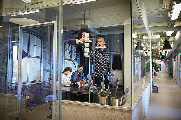 Kreative Geschäftsleute  die im Sitzungssaal arbeiten  durch Glas gesehen