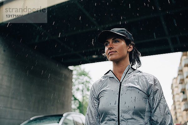 Niedrigwinkelansicht einer Sportlerin  die während der Regenzeit von der Brücke wegschaut