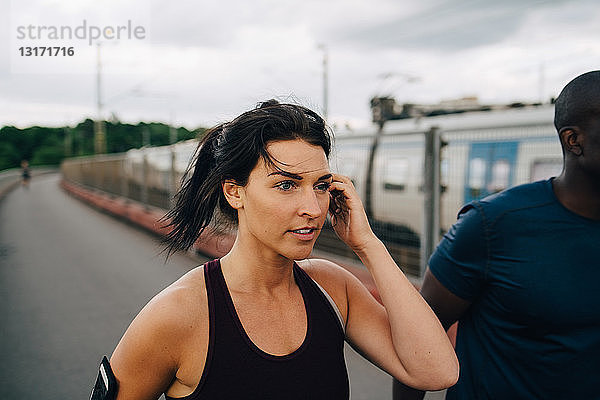 Junge Sportlerin schaut weg  während sie mit einem Freund auf dem Steg joggt
