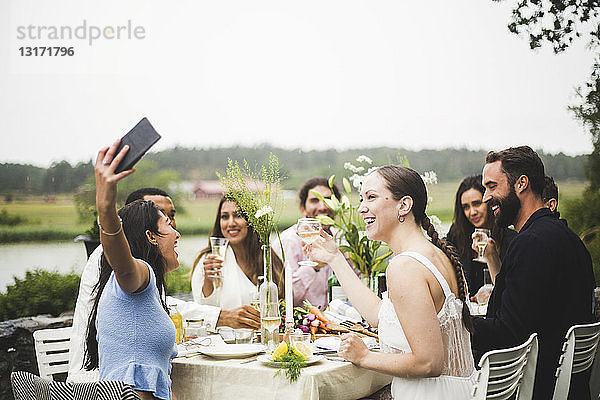 Fröhliche junge Frau  die sich während einer Dinner-Party im Hinterhof mit Freunden zum Selbermachen verabredet