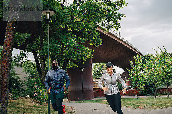 Männliche und weibliche Athleten laufen auf einem Fußweg in der Stadt
