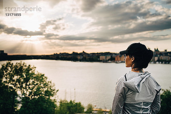 Weibliche Sportlerin schaut weg  während sie auf einem Hügel am Meer gegen den Himmel steht