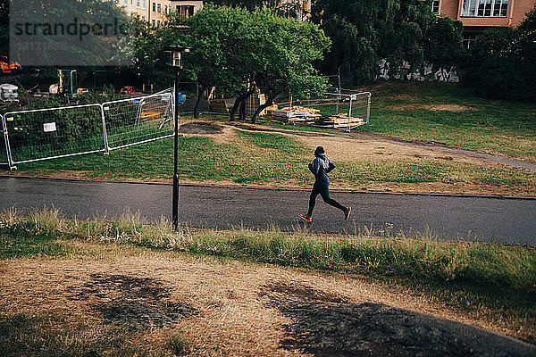 Männlicher Athlet in voller Länge joggt in der Stadt auf der Straße