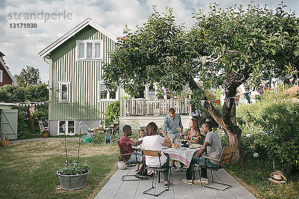 Mehrgenerationen-Familie genießt Getränke auf der Terrasse während einer Gartenparty