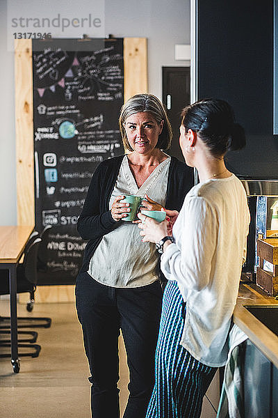 Weibliche Kollegen unterhalten sich beim Kaffee in der Büro-Cafeteria