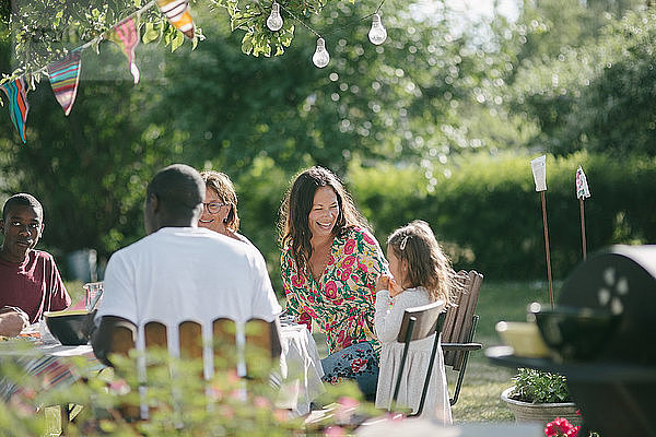 Glückliche Mehrgenerationen-Familie beim gemeinsamen Mittagessen auf der Terrasse während der Gartenparty