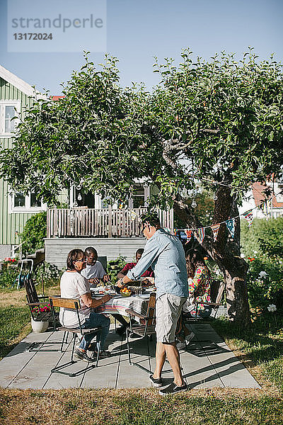 Mehrgenerationen-Familie isst während der Gartenparty gemeinsam auf der Terrasse zu Mittag