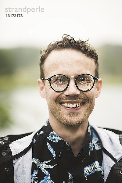Porträt eines lächelnden mittelgroßen Mannes mit Brille während einer Dinnerparty im Hinterhof