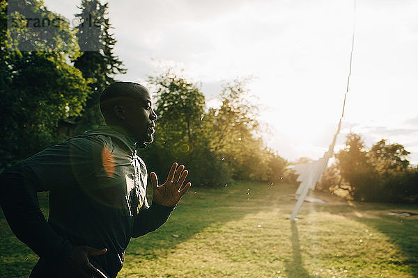 Seitenansicht eines männlichen Athleten  der an einem sonnigen Tag im Park joggt