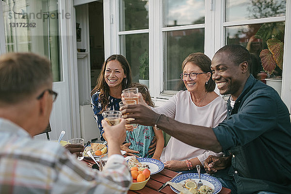 Fröhliche Mehrgenerationen-Familie stößt während der Gartenparty am Tisch auf Getränke an
