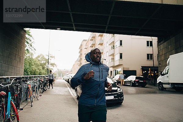 Männlicher Athlet joggt auf dem Bürgersteig in der Stadt