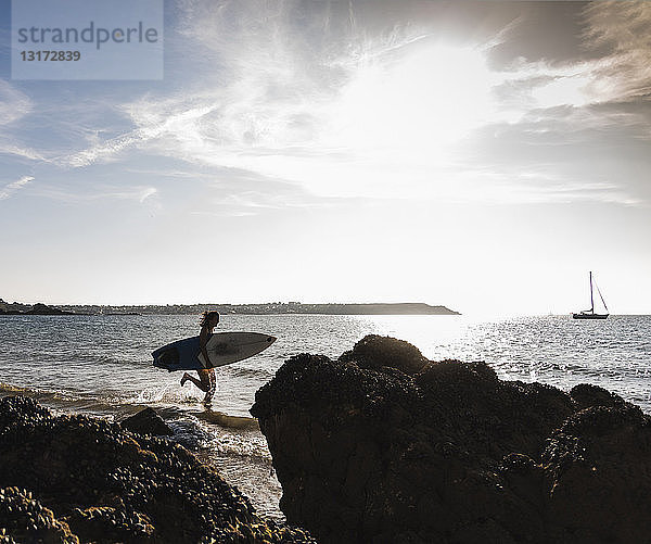 Frankreich  Bretagne  junge Frau mit Surfbrett im Meer