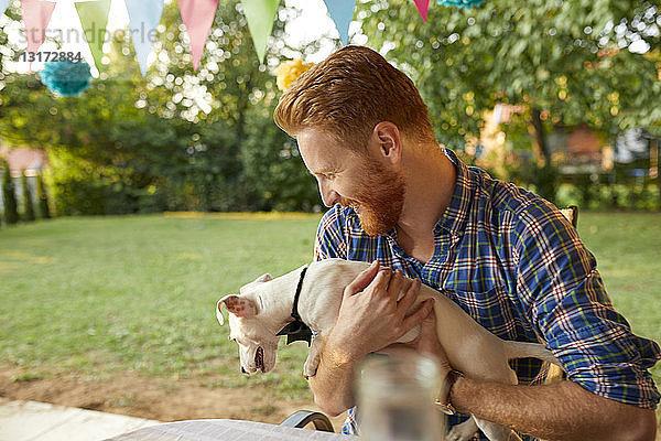 Glücklicher Mann mit Hund auf einer Gartenparty