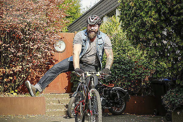 Porträt eines glücklichen Mannes beim Wechsel vom Motorrad aufs Fahrrad