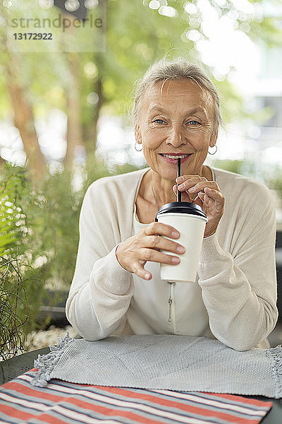 Porträt einer lächelnden älteren Frau in einem Straßencafé