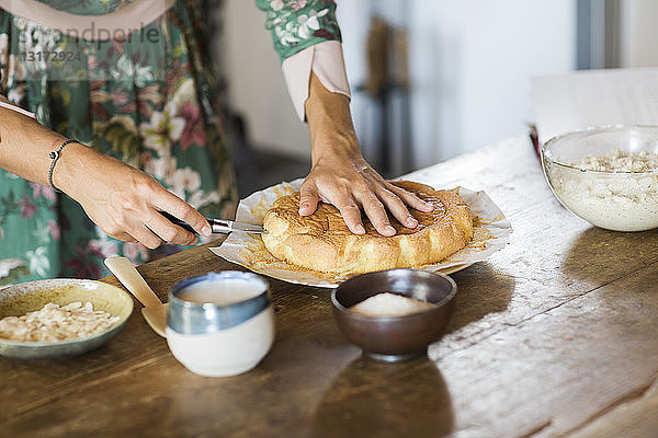 Junge Frau schneidet selbstgebackenen Kuchen an  Teilansicht