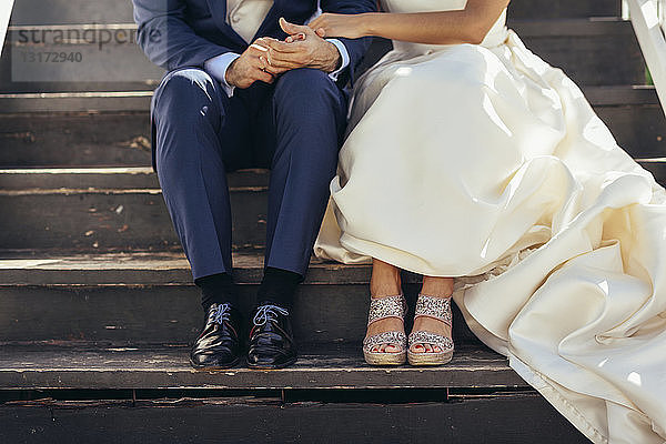 Brautpaar sitzt auf einer Treppe im Freien  Teilansicht