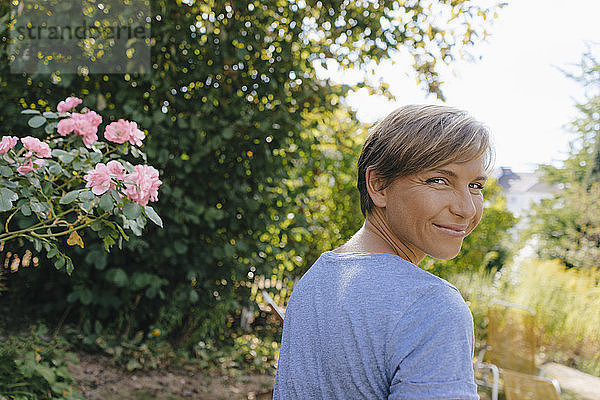 Porträt einer lächelnden Frau im Garten  die sich umdreht