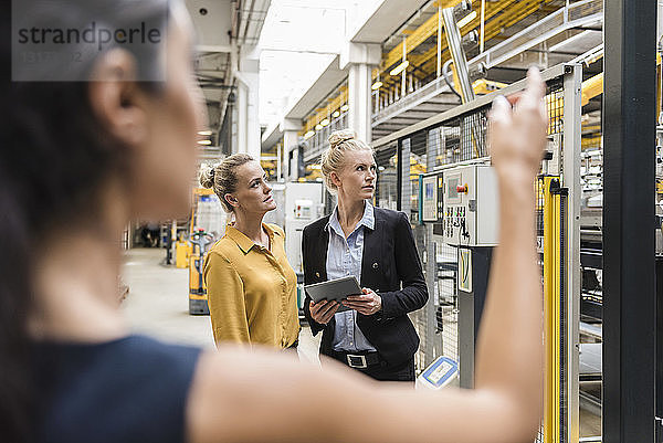 Frauen mit Tabletten sprechen in moderner Fabrik