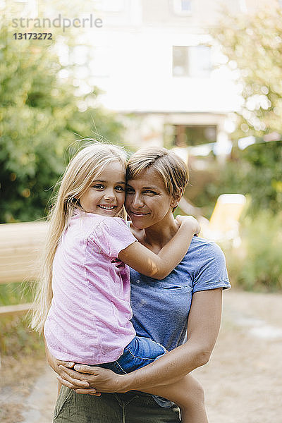 Porträt einer lächelnden Mutter mit Tochter im Garten