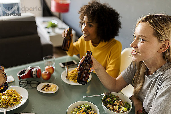 Freundinnen  die am Tisch sitzen  essen und Bier trinken