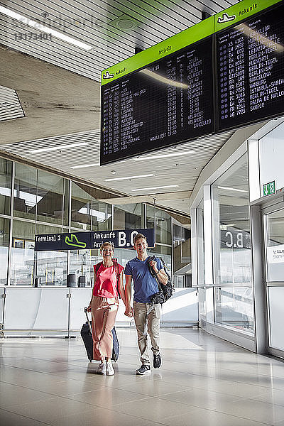 Glückliches Paar geht Hand in Hand auf dem Flughafen