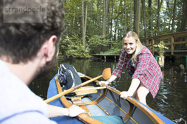 Glückliches junges Paar beim Einsteigen ins Kanu in einem Waldbach