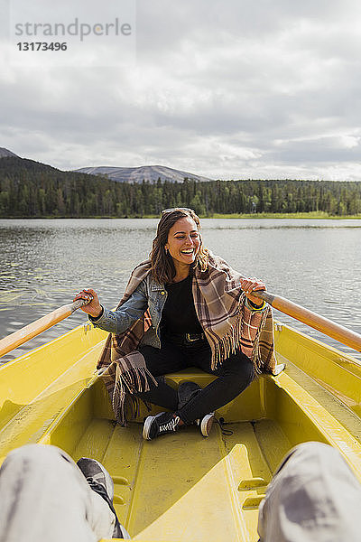 Finnland  Lappland  lachende Frau mit einer Decke in einem Ruderboot auf einem See