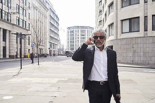 Großbritannien  London  Porträt eines älteren Geschäftsmannes mit Sonnenbrille am Telefon