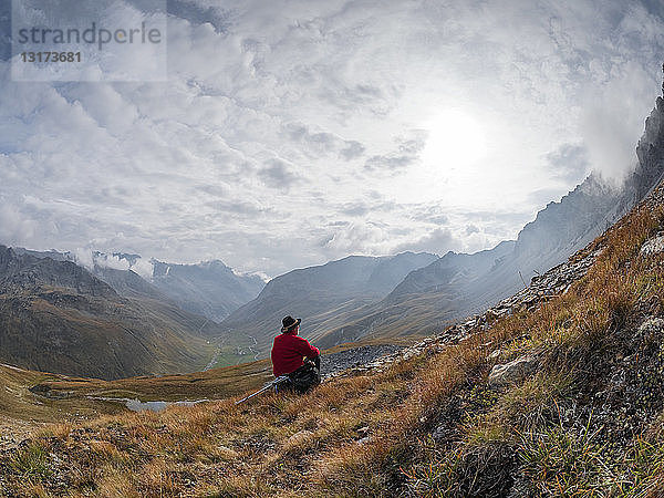 Grenzregion Italien Schweiz  älterer Mann macht Pause vom Wandern in der Berglandschaft am Piz Umbrail