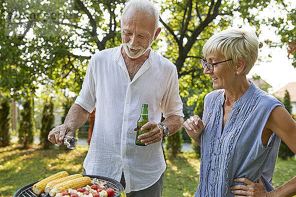 Älteres Ehepaar beim Grillen im Garten