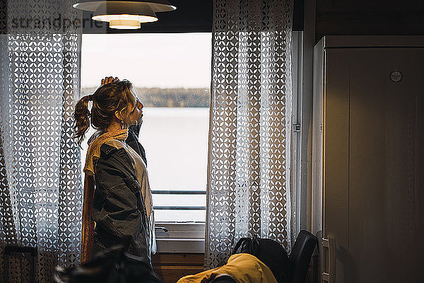 Porträt einer jungen Frau  die in einem Raum mit einem Fenster steht