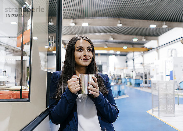 Zuversichtliche Frau  die in einem High-Tech-Unternehmen arbeitet und Kaffee trinkt