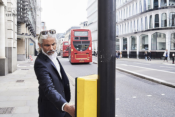 UK  London  bärtiger leitender Geschäftsmann drückt Ampelknopf
