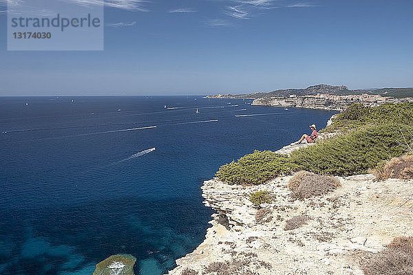 Korsika  Mittelmeerküste  Frau sitzt auf einer Felsklippe