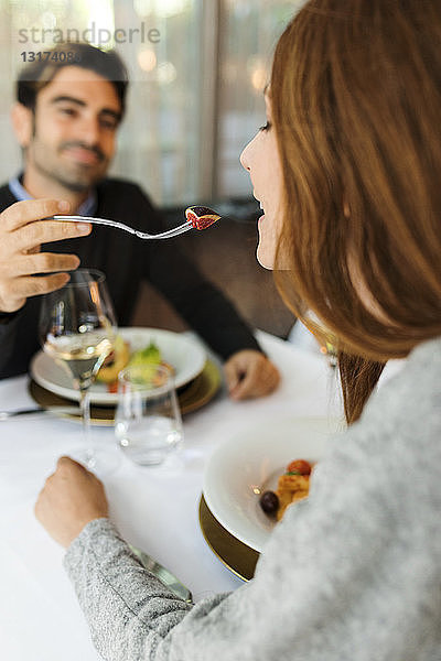 Mann lässt Frau das Essen in einem Restaurant kosten