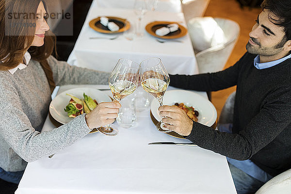 Lächelndes Paar beim Anstossen von Weingläsern in einem Restaurant