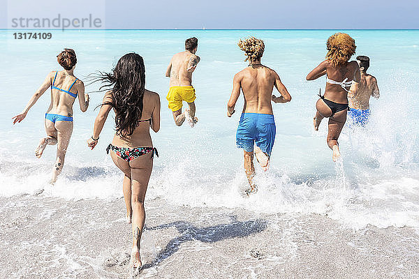 Gruppe von Freunden  die sich am Strand vergnügen und ins Wasser laufen
