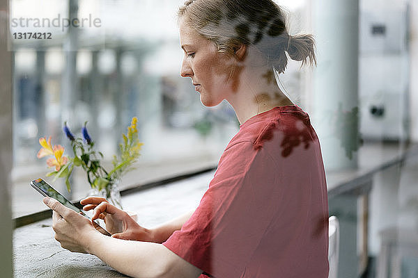 Junge Frau mit Tablette am Fenster in einem Cafe