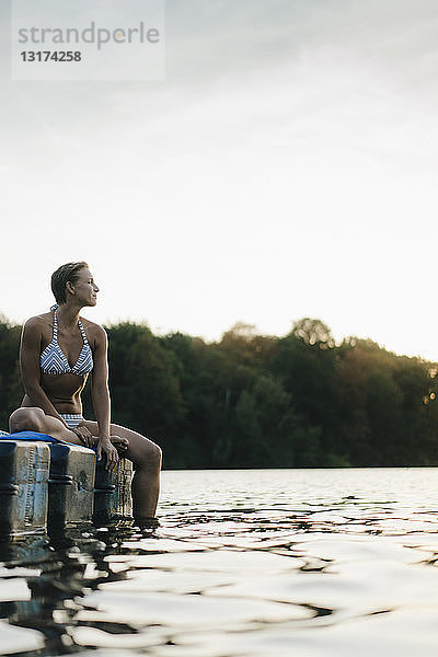 Frau im Bikini  die auf einem Schwimmer auf einem See sitzt