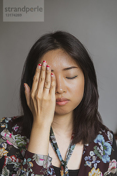 Porträt einer Frau  die das Auge mit der Hand bedeckt
