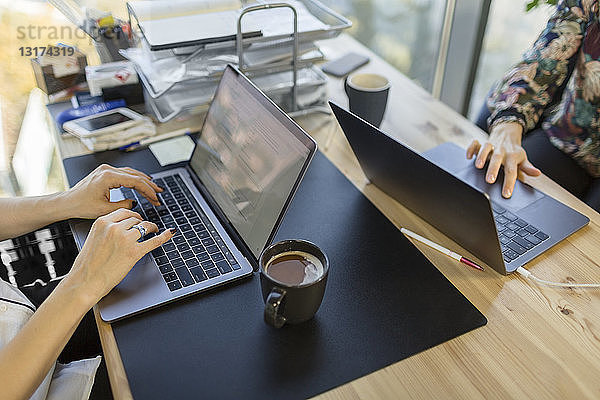 Nahaufnahme von zwei Frauen  die Laptops am Schreibtisch im Büro benutzen