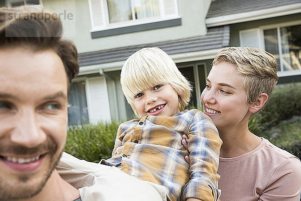 Porträt von glücklichen Eltern mit Sohn vor ihrem Haus